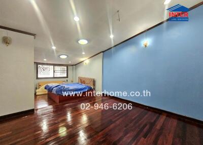 spacious bedroom with wooden flooring and blue accent wall