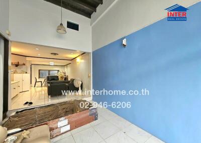 Living room with blue accent wall, ceiling light, and visible kitchen area