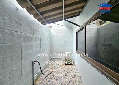 Small outdoor area with tiled floor and water hose