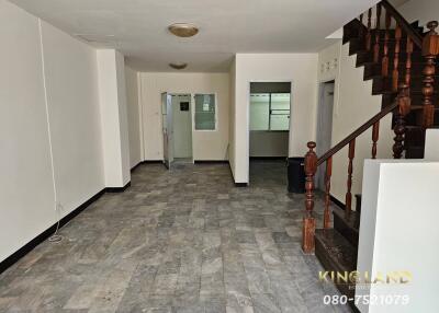 Spacious living area with tiled floor and wooden staircase.