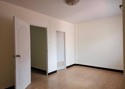 Bedroom with open door, beige tiles, and cream walls