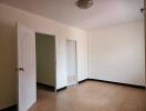 Bedroom with open door, beige tiles, and cream walls