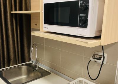 Simple kitchen setup with microwave, sink, and dish rack