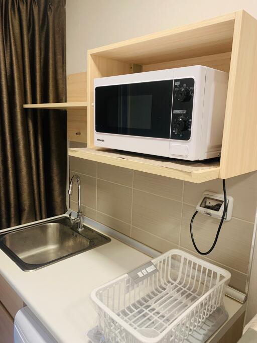 Compact kitchen area with sink, microwave, and dish rack