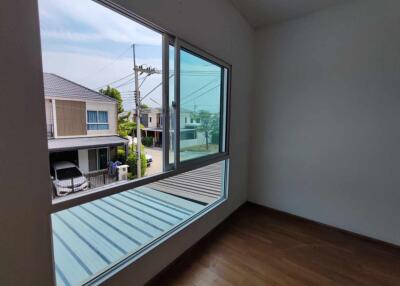 Empty room with large window overlooking neighborhood