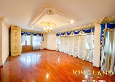 Spacious, well-lit living room with wooden flooring and decorative curtains