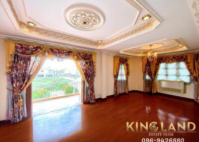 spacious living room with ornate ceiling and large windows with curtains