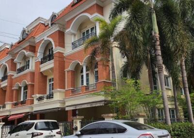 Front exterior of a multi-story residential building with parked cars