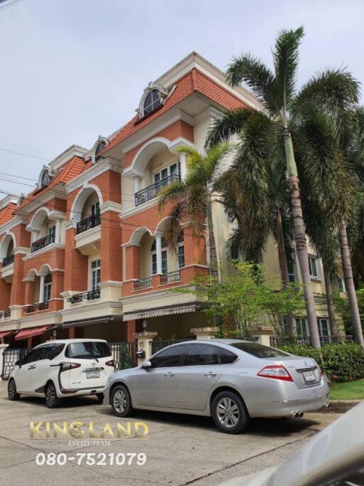 Front exterior of a multi-story residential building with parked cars