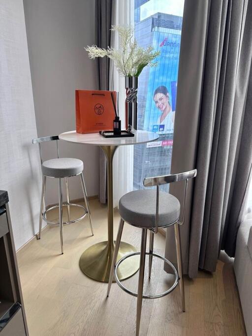 Modern dining area with a small round table and two stylish stools by a window with a city view.