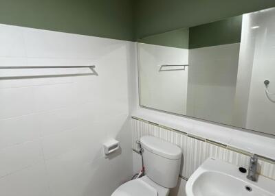 Modern bathroom with toilet, sink, mirror, and tiled floor