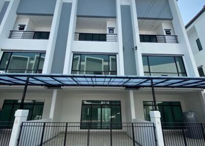 Modern three-story townhouse exterior with balconies and carport