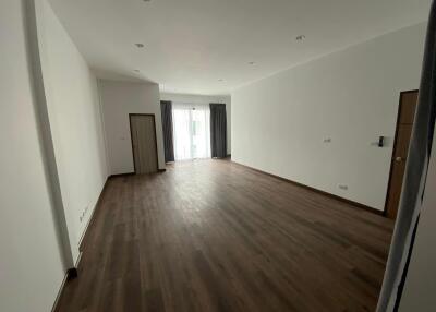 Spacious empty living room with wooden flooring and large windows