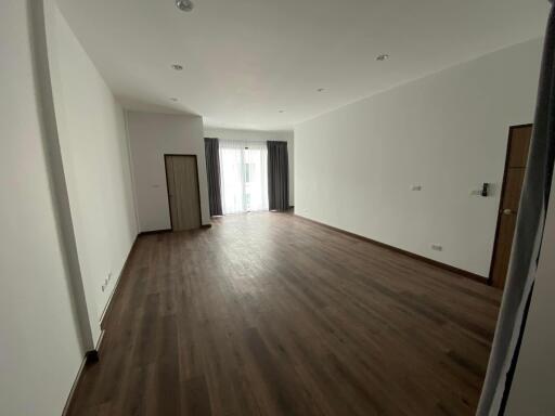 Spacious empty living room with wooden flooring and large windows