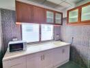 Modern kitchen with upper and lower cabinets, a microwave, and a clean countertop