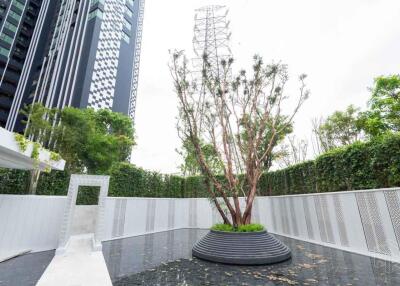 Modern outdoor area with greenery and tall buildings in the background