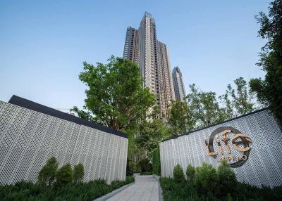 Modern high-rise building exterior with sign and greenery