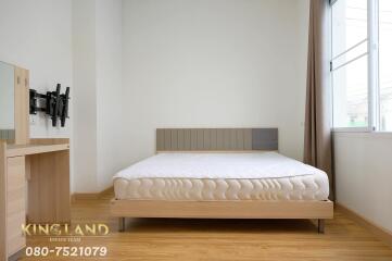 Modern bedroom with a double bed, window, dresser, and mounted TV stand