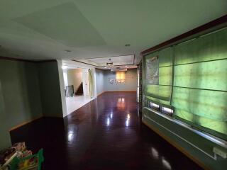 Spacious living room with dark wooden flooring, green blinds, and good natural lighting