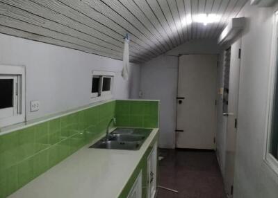 Narrow kitchen with green backsplash and white cabinetry