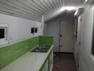 Narrow kitchen with green backsplash and white cabinetry