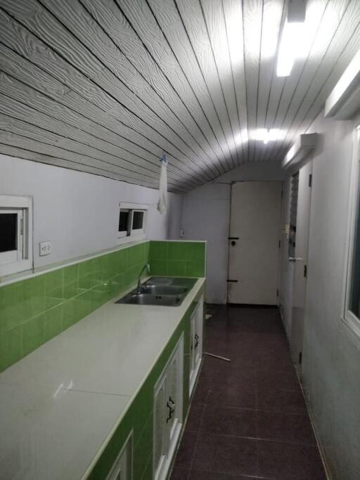 Narrow kitchen with green backsplash and white cabinetry