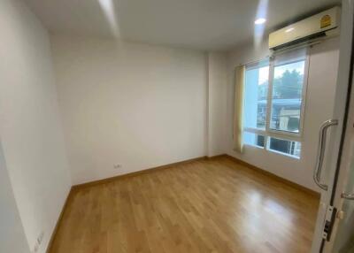 Empty bedroom with wooden flooring, a large window, and an air conditioning unit