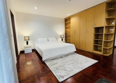 Modern bedroom with wooden floors, built-in wardrobe, and white bedding