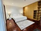 Modern bedroom with wooden floors, built-in wardrobe, and white bedding