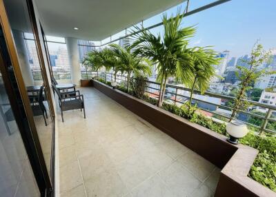 Spacious balcony with seating area and potted plants offering city views