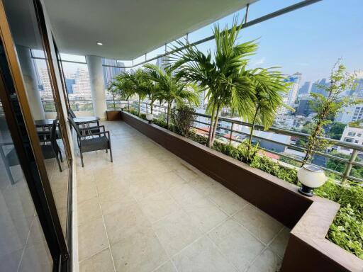 Spacious balcony with seating area and potted plants offering city views