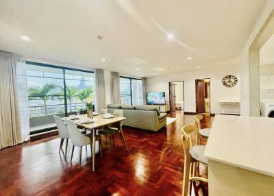 Spacious and well-lit living room with dining area, large windows, and balcony view