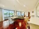 Spacious and well-lit living room with dining area, large windows, and balcony view