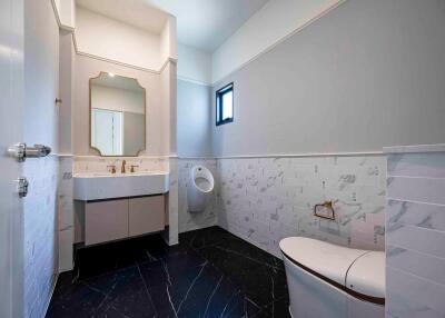 Modern bathroom with black floor tiles, a large mirror, and a spacious sink