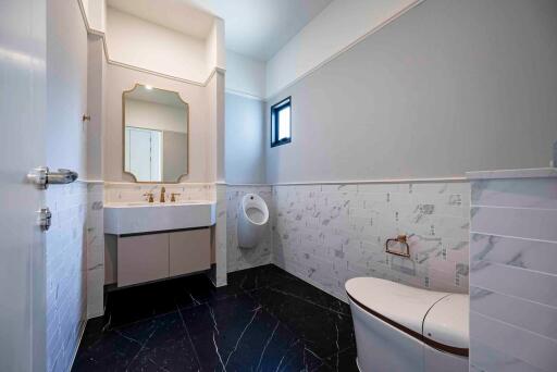 Modern bathroom with black floor tiles, a large mirror, and a spacious sink