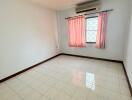 Empty bedroom with tiled floor and window with pink curtains