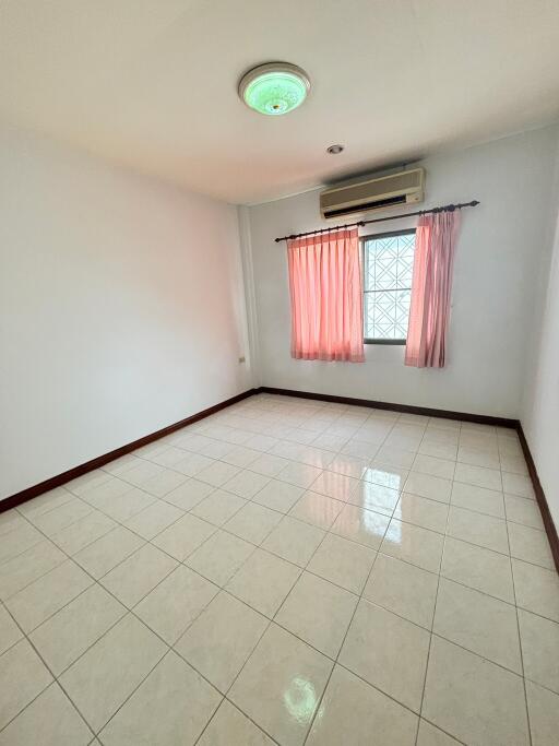 Empty bedroom with tiled floor and window with pink curtains