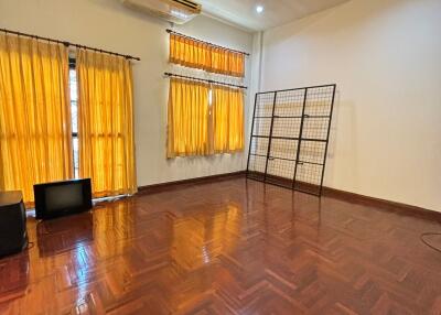 Spacious living room with wooden flooring, bright curtains, and ceiling lighting