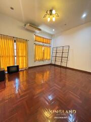 Spacious living room with wooden flooring and large windows with yellow curtains