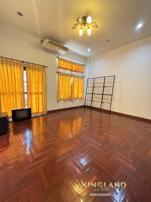 Spacious living room with wooden flooring and large windows with yellow curtains