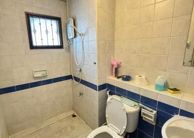 Bathroom with tiled walls, toilet, sink, and shower