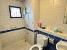 Bathroom with tiled walls, toilet, sink, and shower