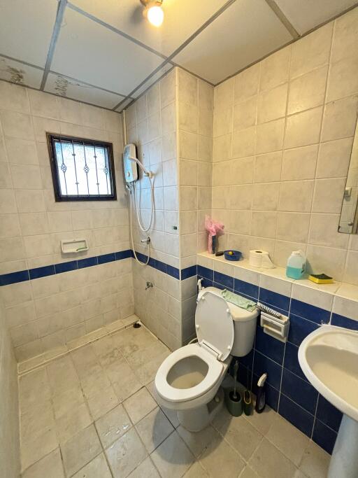 Bathroom with tiled walls, toilet, sink, and shower