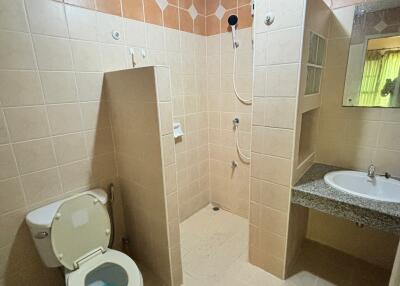 Spacious bathroom with tiled walls, walk-in shower, toilet, and sink