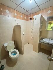 Spacious bathroom with tiled walls, walk-in shower, toilet, and sink