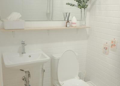 Modern bathroom with white tiles, a large mirror, and a small sink