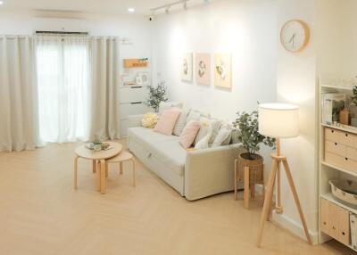 Spacious and well-lit living room with a white sofa, coffee table, floor lamp, and wall decorations.