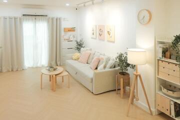 Spacious and well-lit living room with a white sofa, coffee table, floor lamp, and wall decorations.