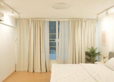 Spacious bedroom with large windows and full-length curtains