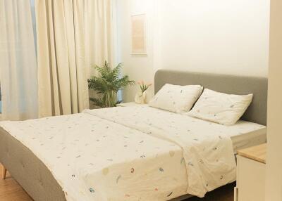 Modern bedroom with a king-size bed, white curtains, and wooden floor